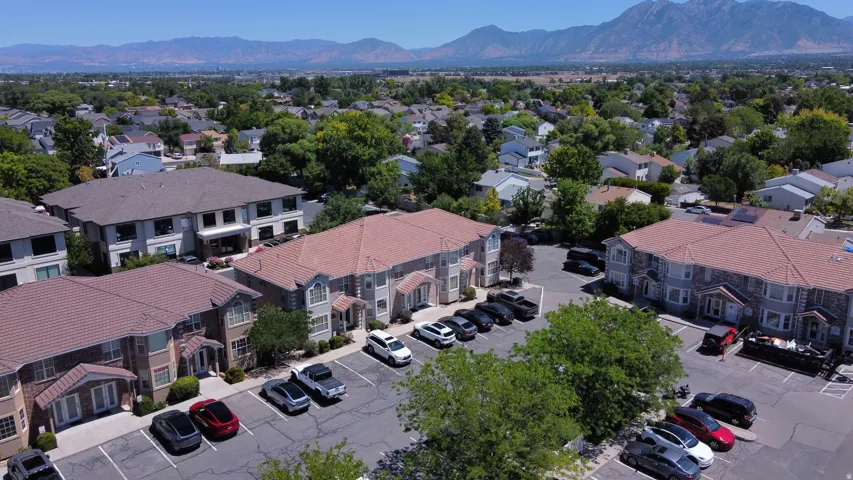 Mountain range backdrop complementing residential properties with pitched roofs, mature trees, and ample paved parking