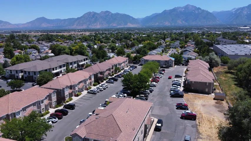 Apartment complex with multiple buildings, paved parking areas, and a mountainous backdrop