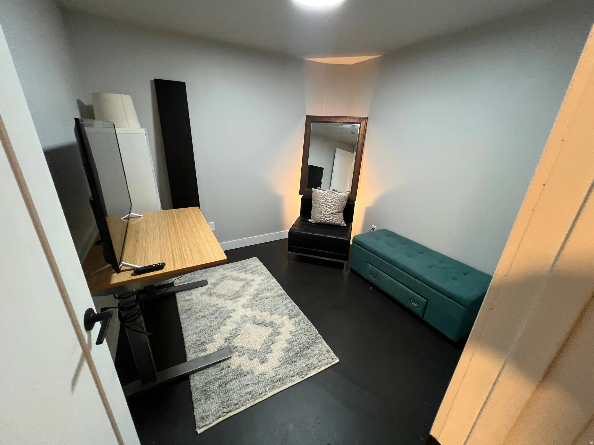 Dark-toned flooring, light-toned wall paint, and a corner-fitted light fixture