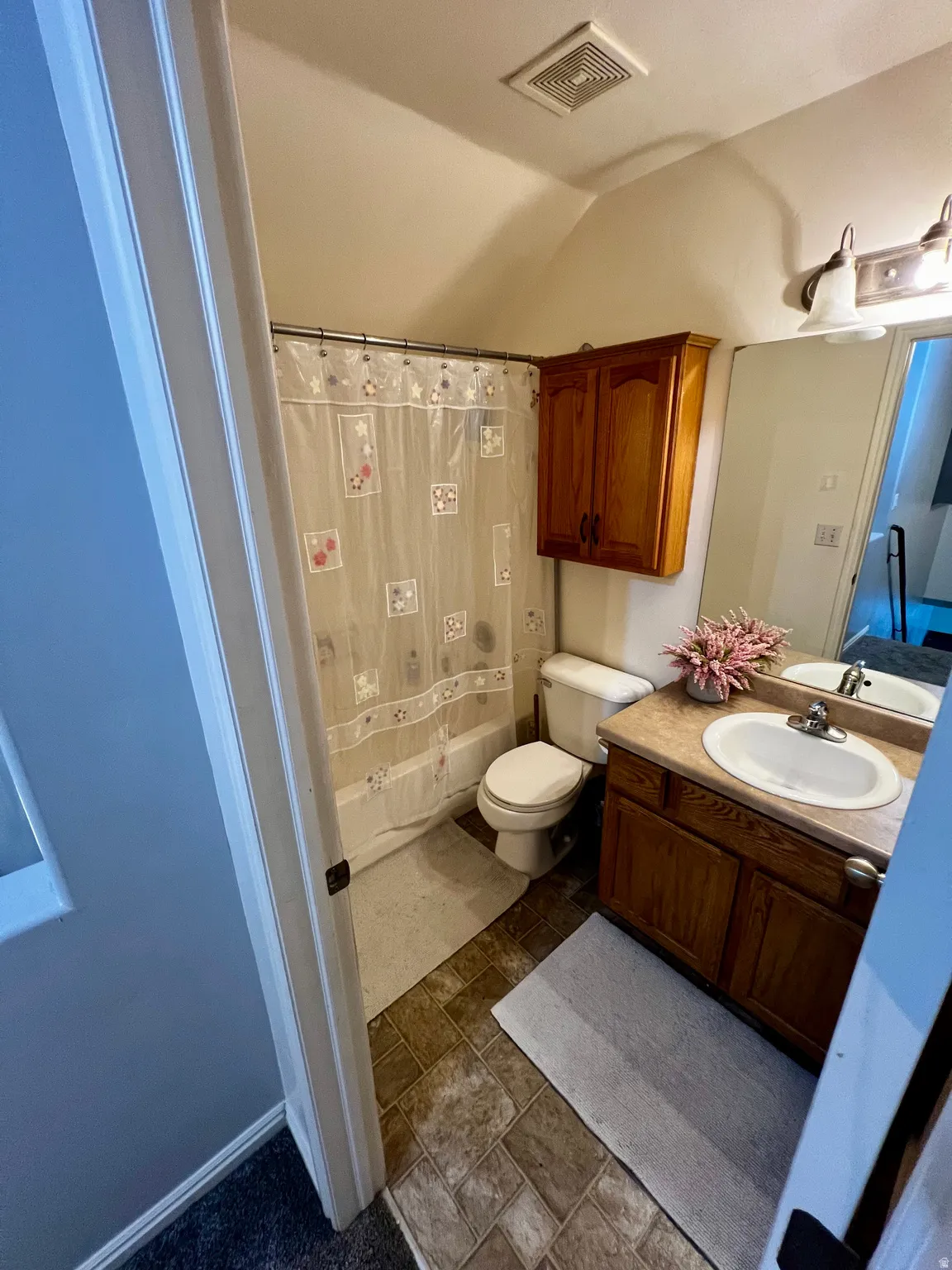 Bathroom featuring a single vanity, wood-finish cabinetry, and a shower-tub combination