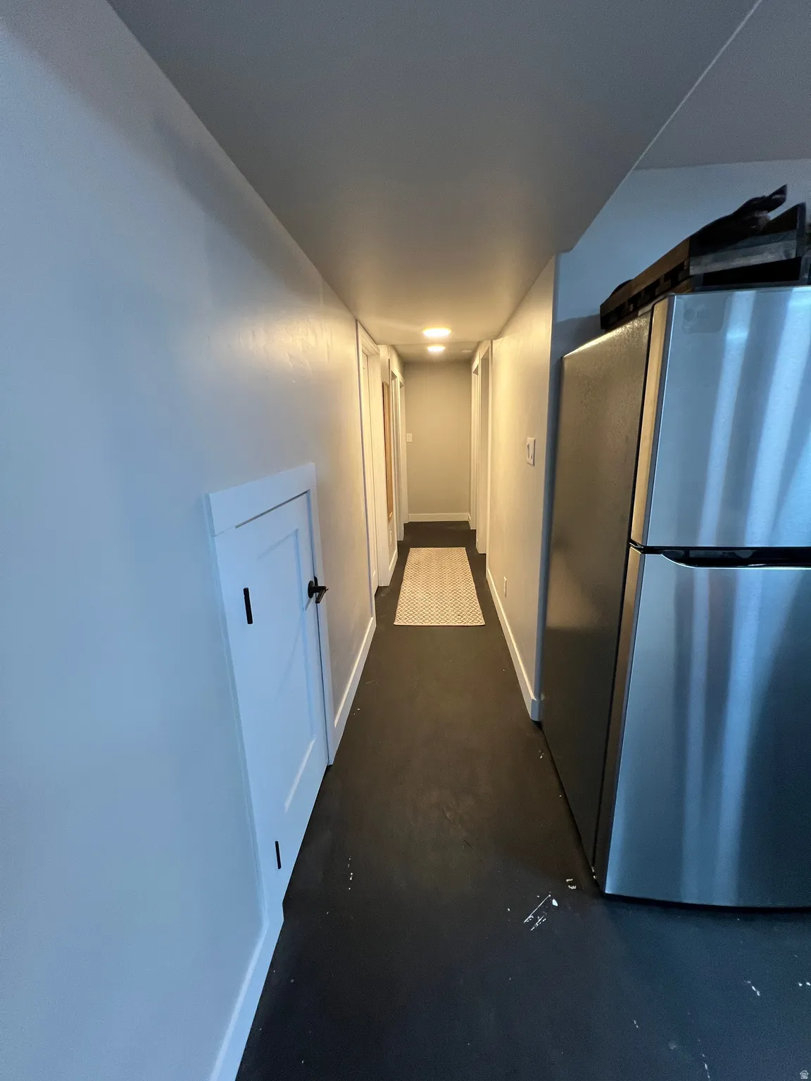 Hallway with recessed lighting, black flooring, and white trim