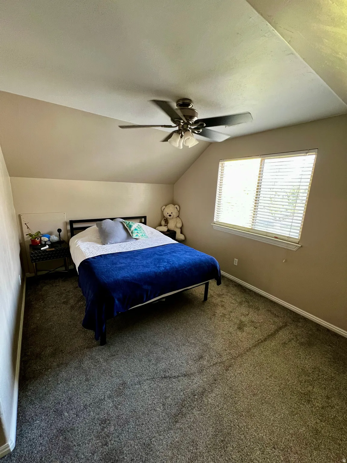 Sloped ceilings, window with blinds, ceiling fan with light fixture, and wall-to-wall carpeting