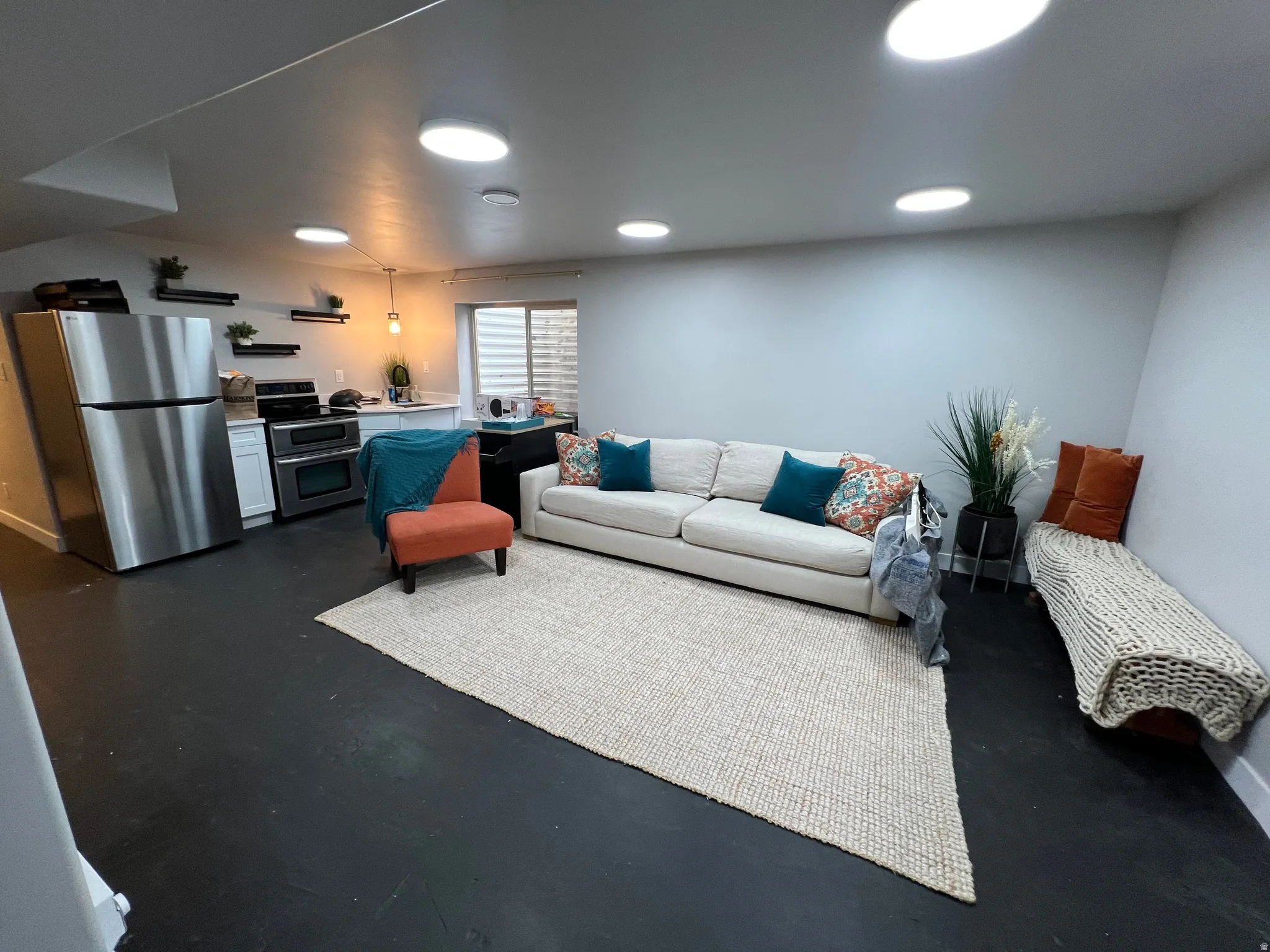 Recessed lighting, stainless steel appliances, white cabinetry, dark flooring, and a built-in window bench