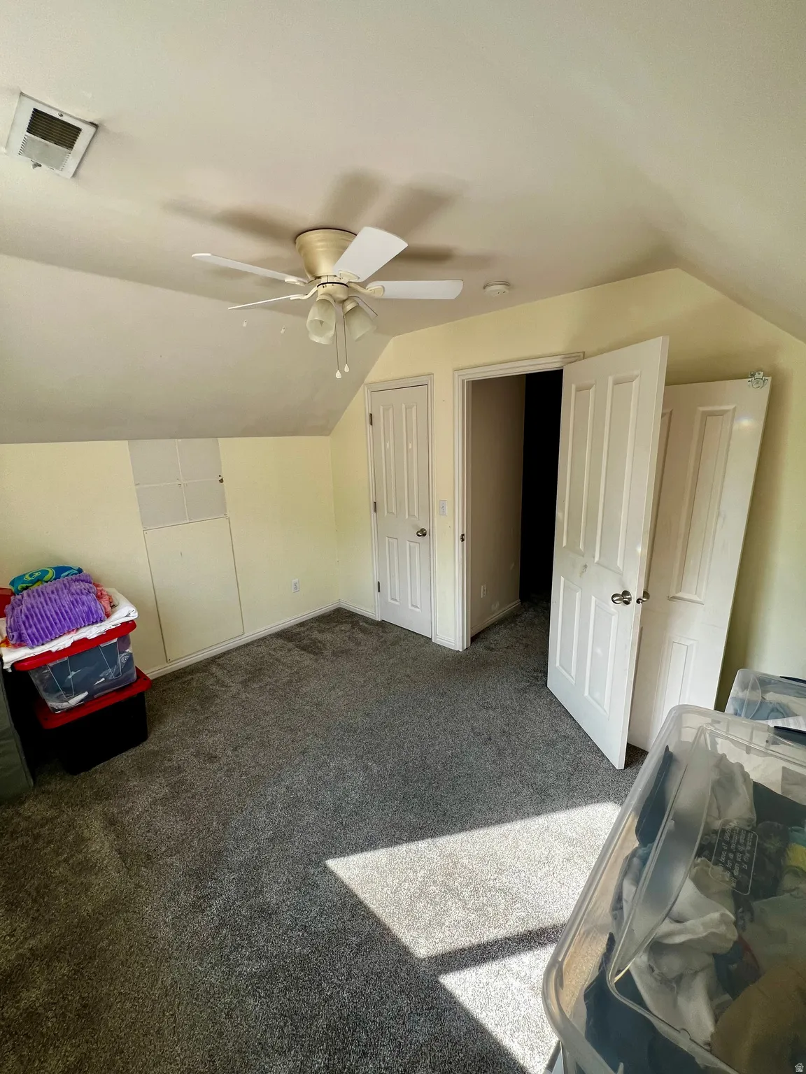 Angled ceilings, light-toned walls, and a ceiling fan with light fixture