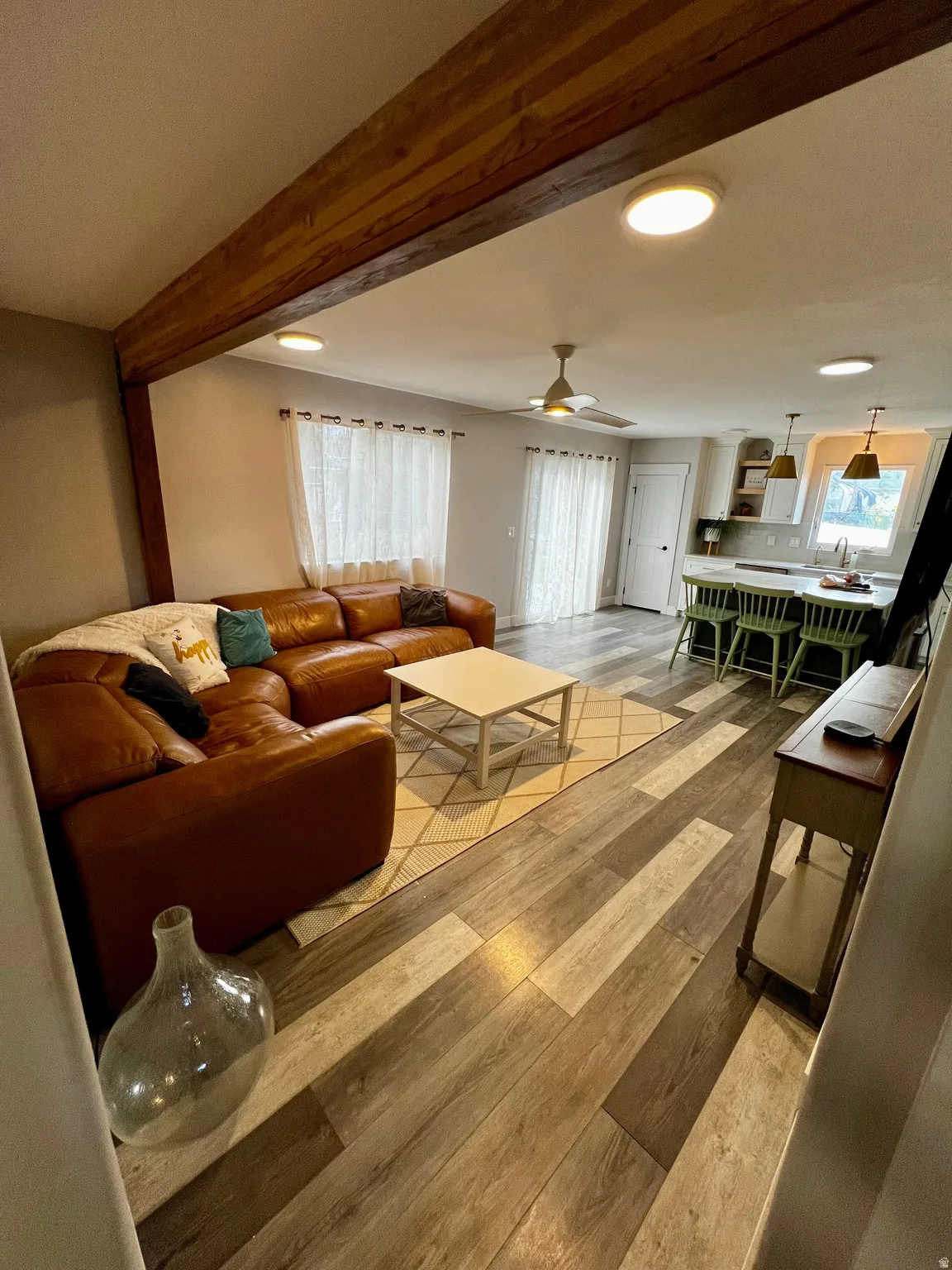Open concept living area featuring wood-finish flooring, recessed lighting, and a prominent wood beam accent