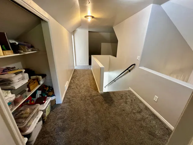 Carpeted attic space with sloped ceilings and built-in shelving
