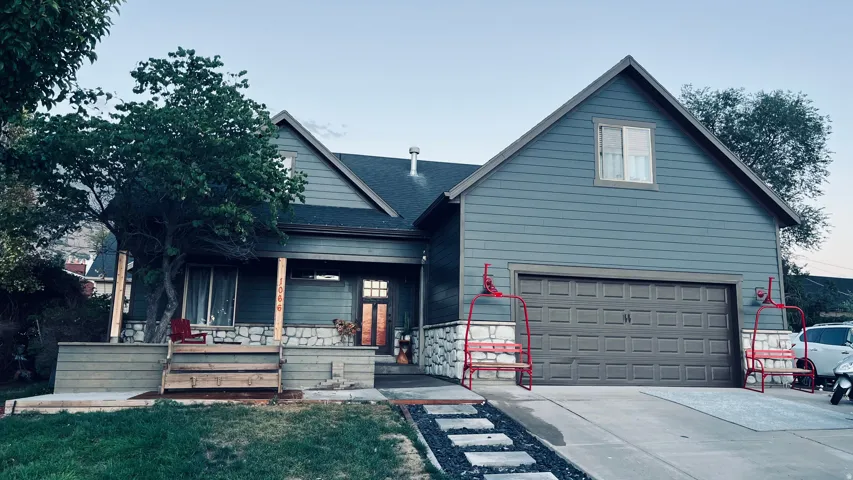 Two-story exterior with siding and stone accents, featuring a covered porch, an attached garage, and a concrete driveway