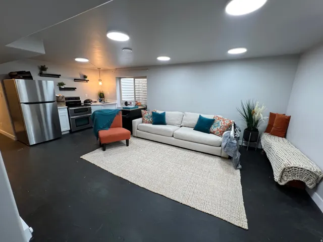 Recessed lighting, stainless steel appliances, white cabinetry, dark flooring, and a built-in window bench