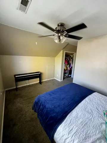 Carpeted flooring, vaulted ceiling, built-in ceiling fan with lighting, and a closet with bifold door