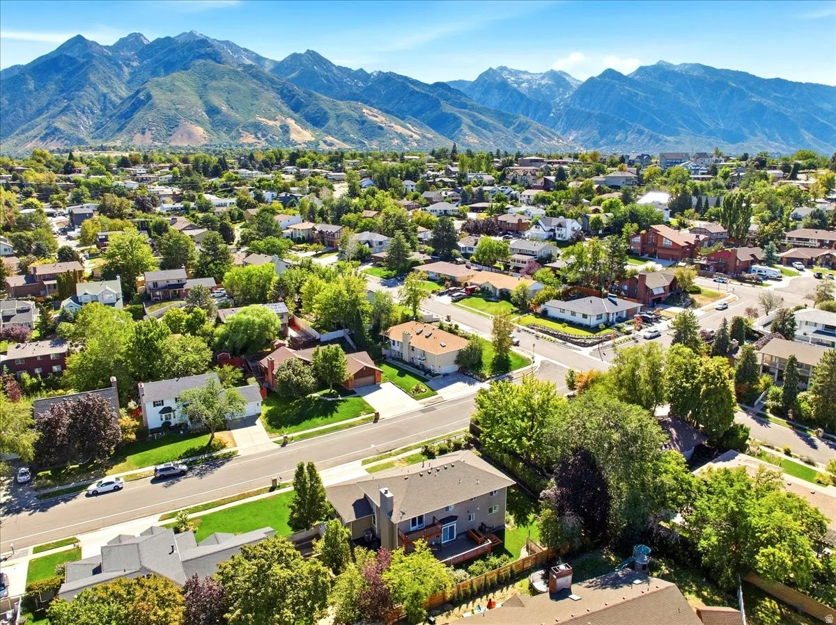 Residential neighborhood with mature trees, paved streets, and mountainous backdrop