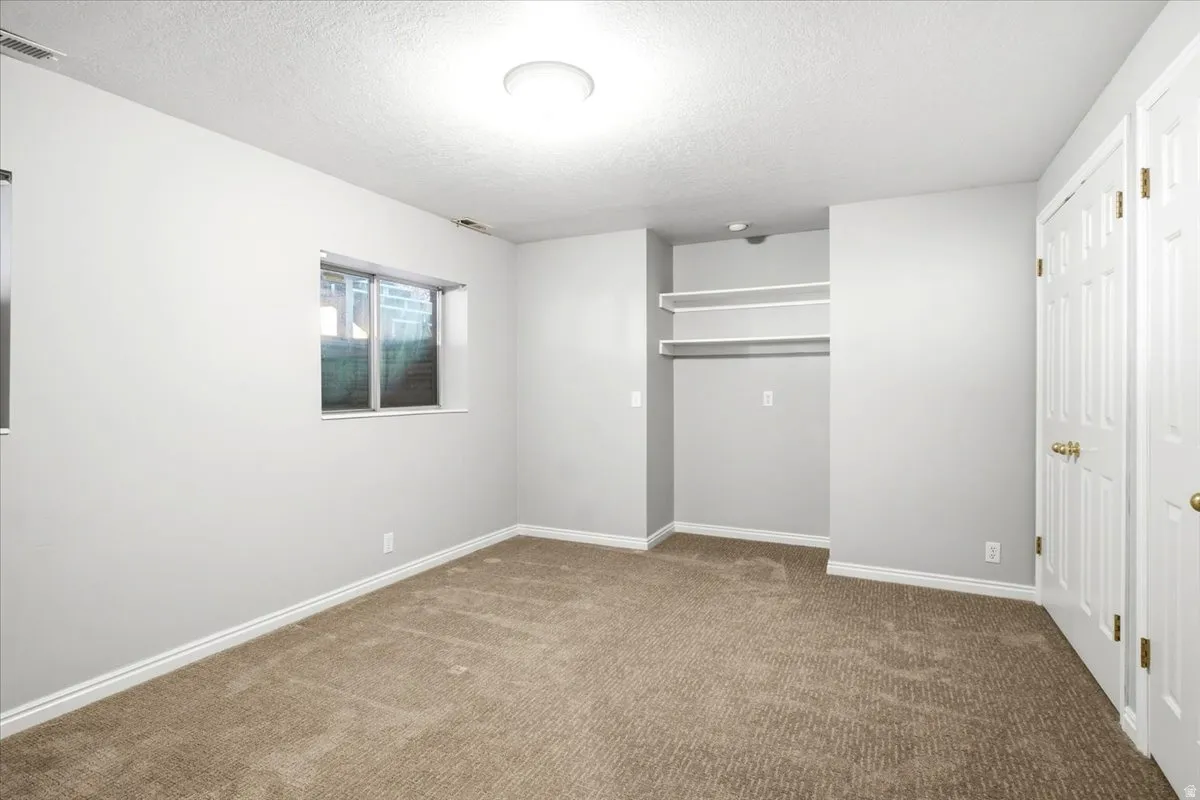 Carpeted room with light neutral walls, a built-in closet with shelving, and two windows