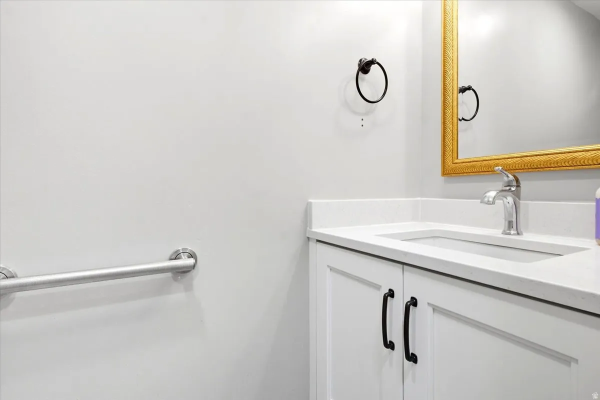 White vanity with shaker-style cabinet doors, dark-finish hardware, and an integrated rectangular sink