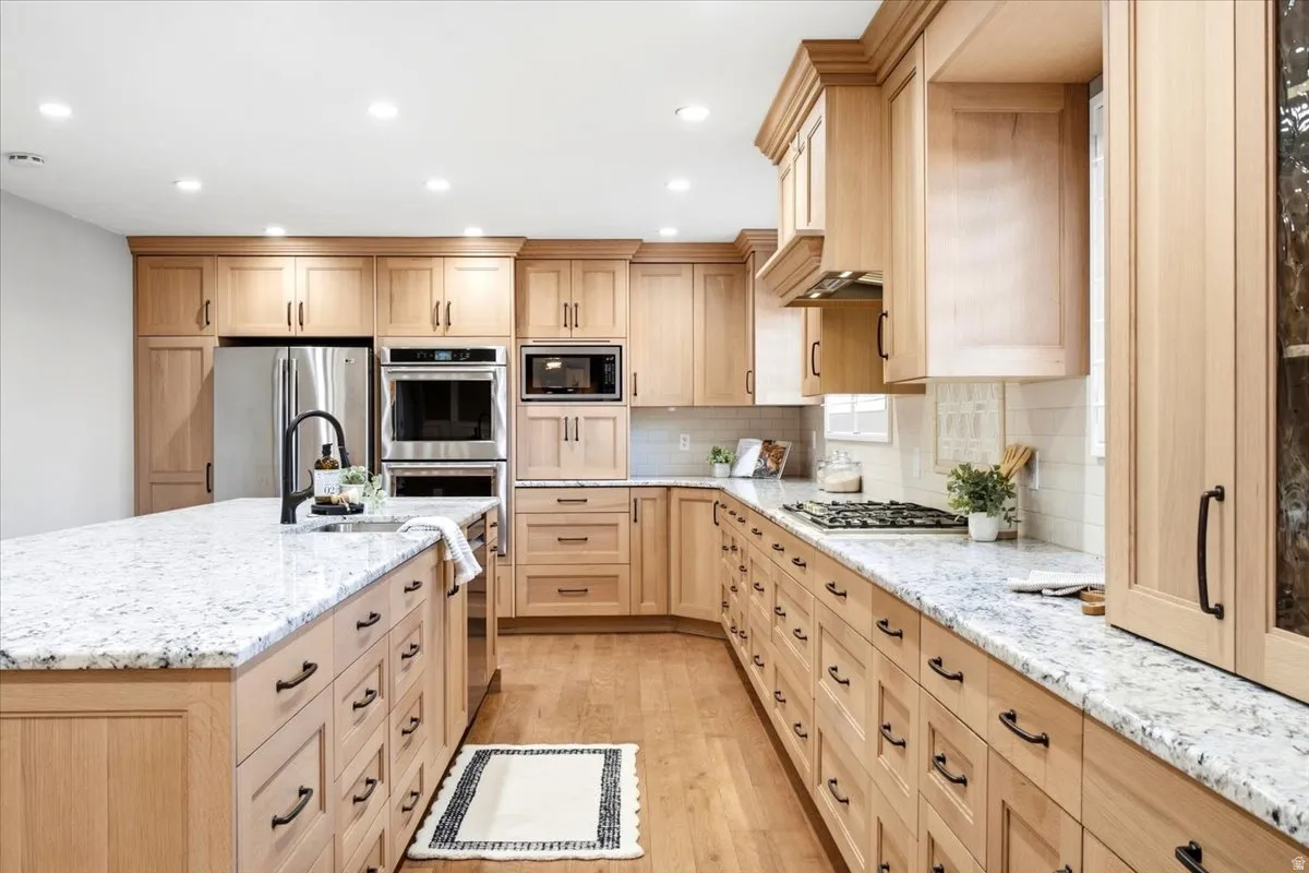 Kitchen featuring light wood cabinetry, light-colored countertops, stainless steel appliances, a built-in microwave, and recessed lighting