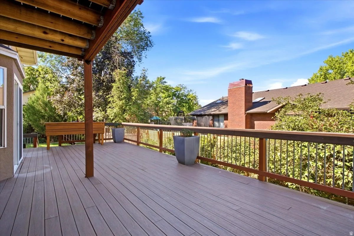 Expansive outdoor deck with composite decking, wood railing, and a covered patio area