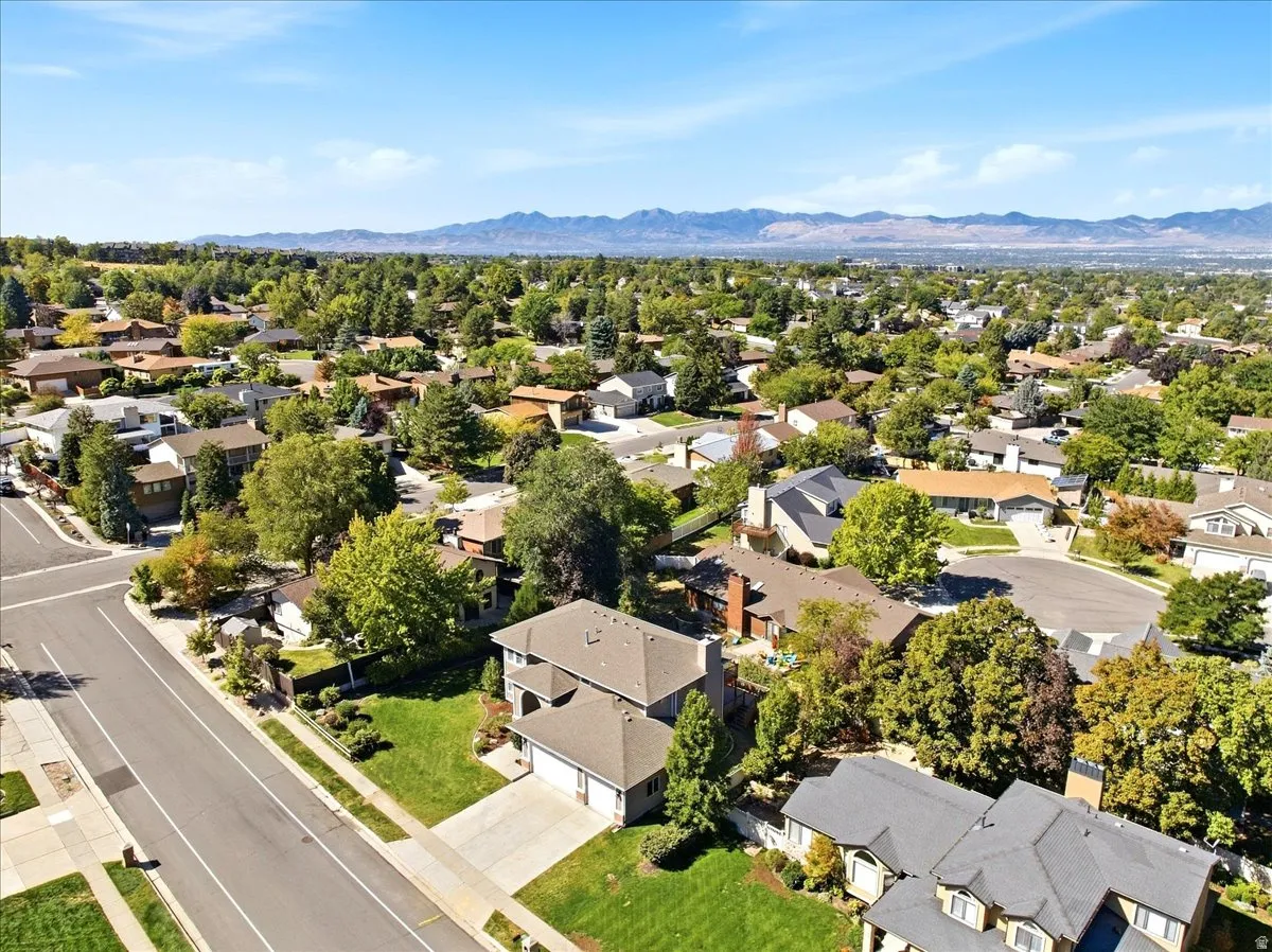 Residential neighborhood with mature trees, paved streets, and distant mountains