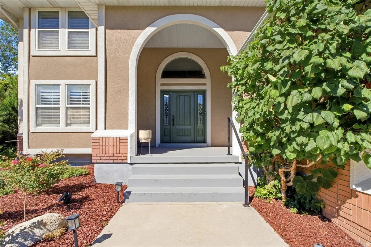 Stucco exterior with an arched entry, a paneled front door with sidelights, and a brick accent foundation