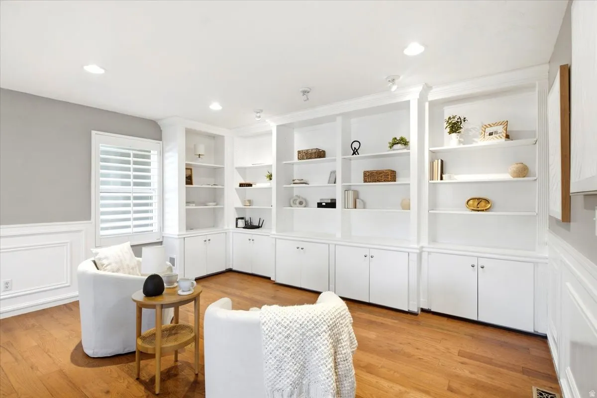 Built-in white shelving and cabinetry, recessed lighting, wood-finish flooring, plantation shutters, and wainscoting with decorative molding