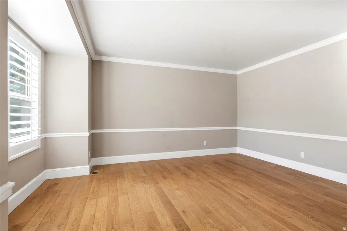 Hardwood flooring, crown molding, chair rail detailing, neutral wall tones, and plantation shutters