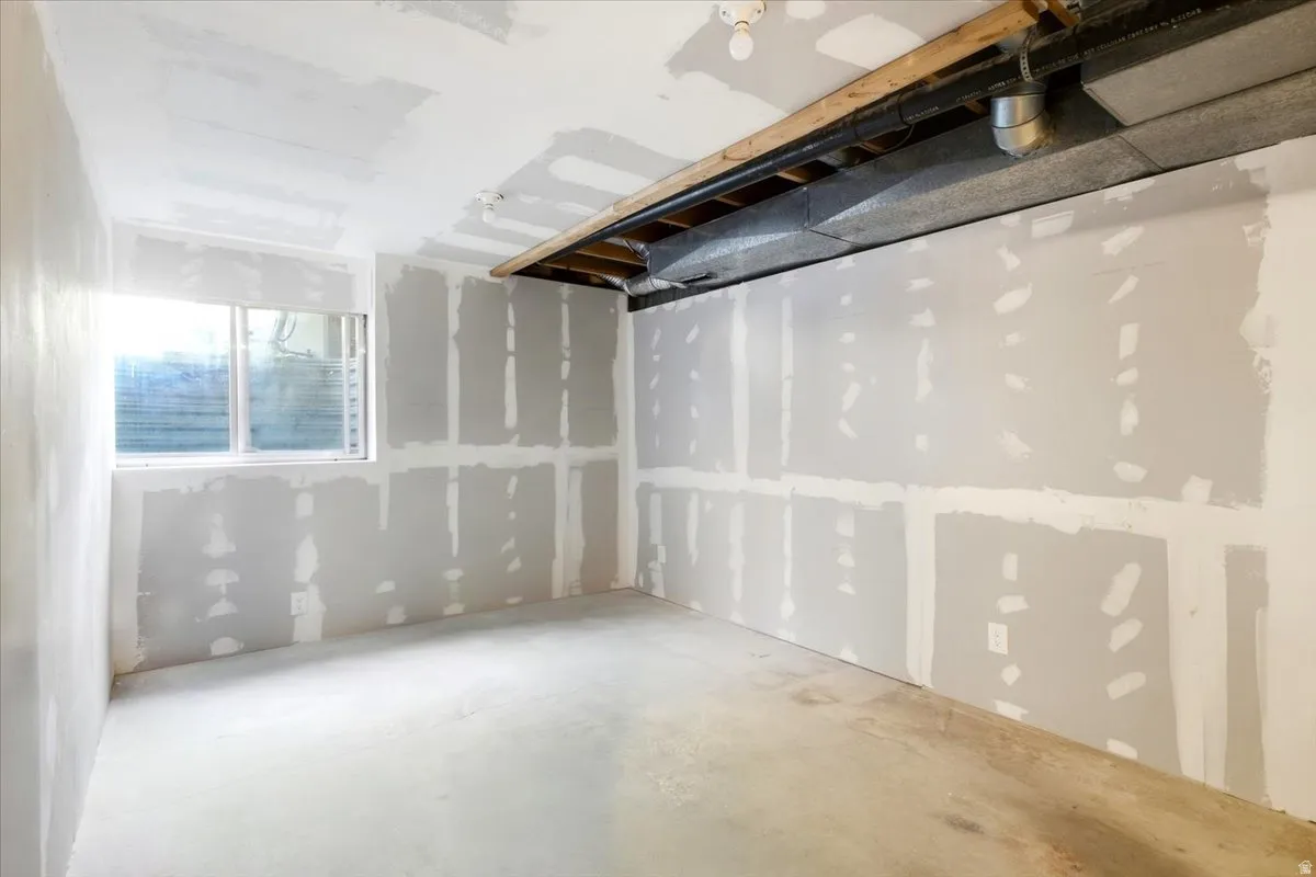 Room featuring drywall installation, exposed ceiling joists, and a window