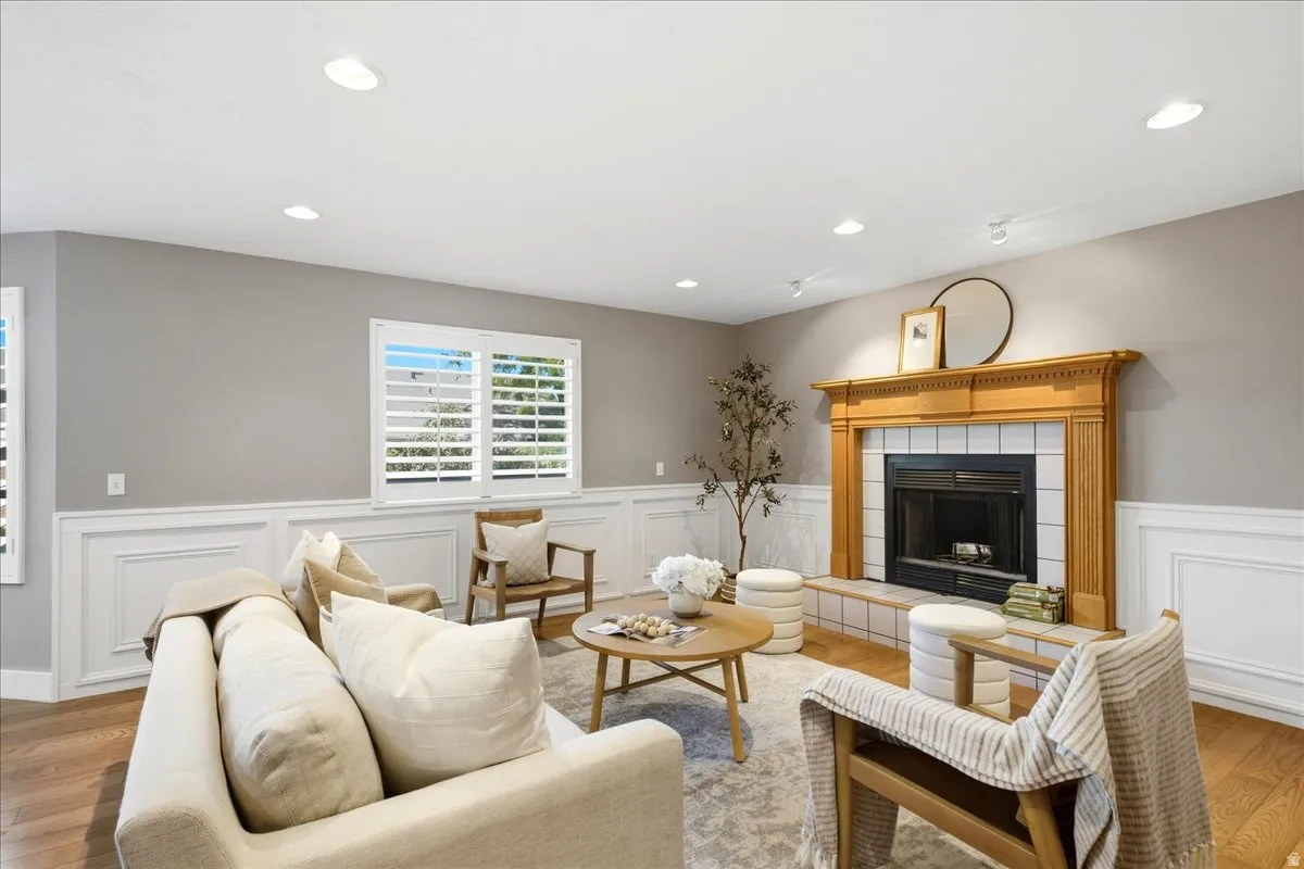 Recessed lighting illuminates the room, featuring wood-finish flooring, wainscoting, and window shutters