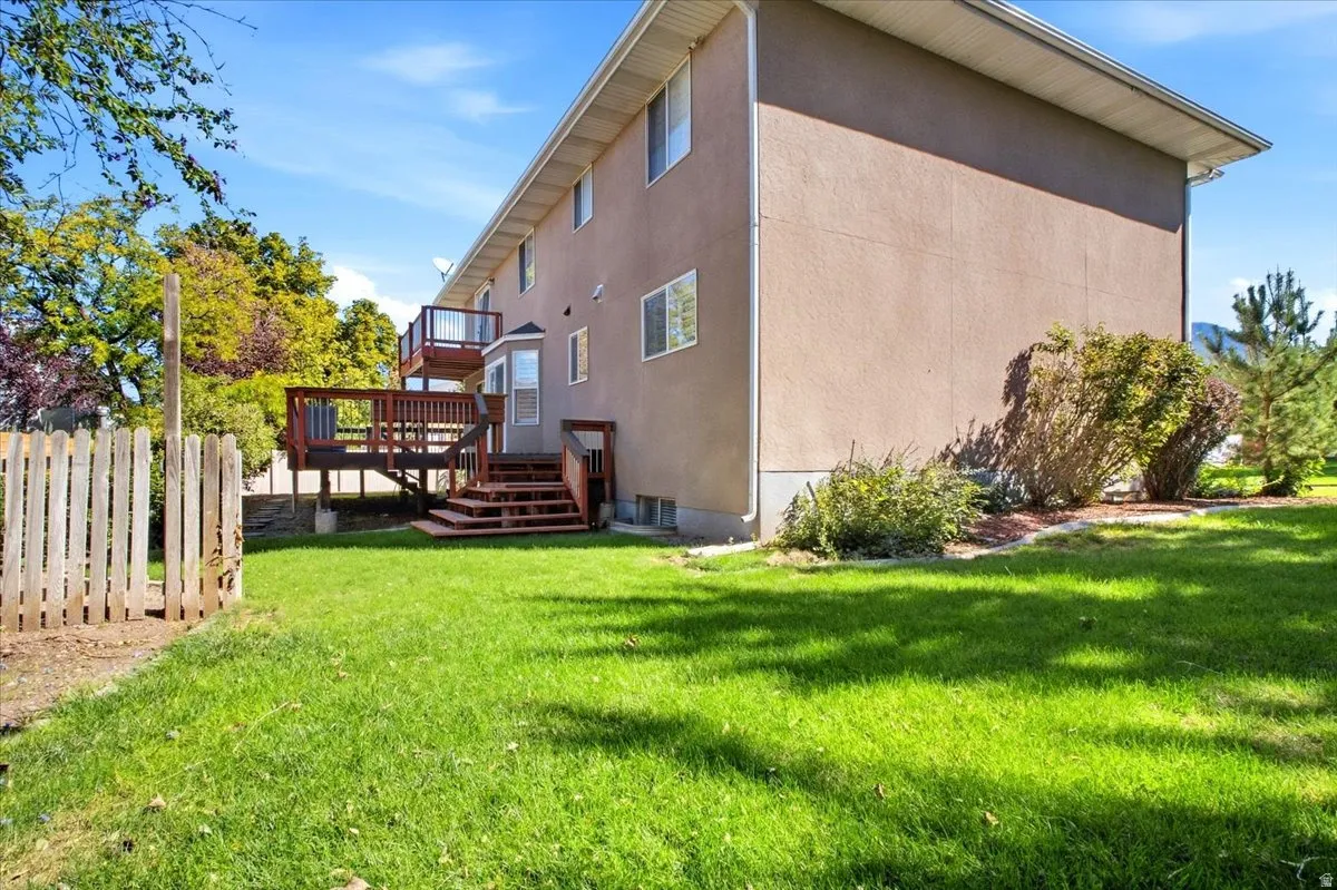 Multi-level wood deck with stairs, stucco exterior, multiple windows, and a bay window