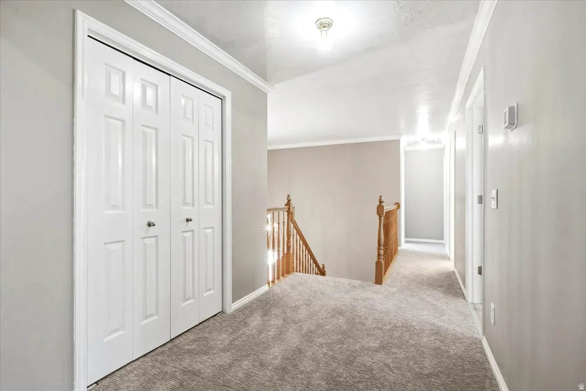 Carpeted hallway with a bi-fold closet, recessed lighting, and a wood spindle railing