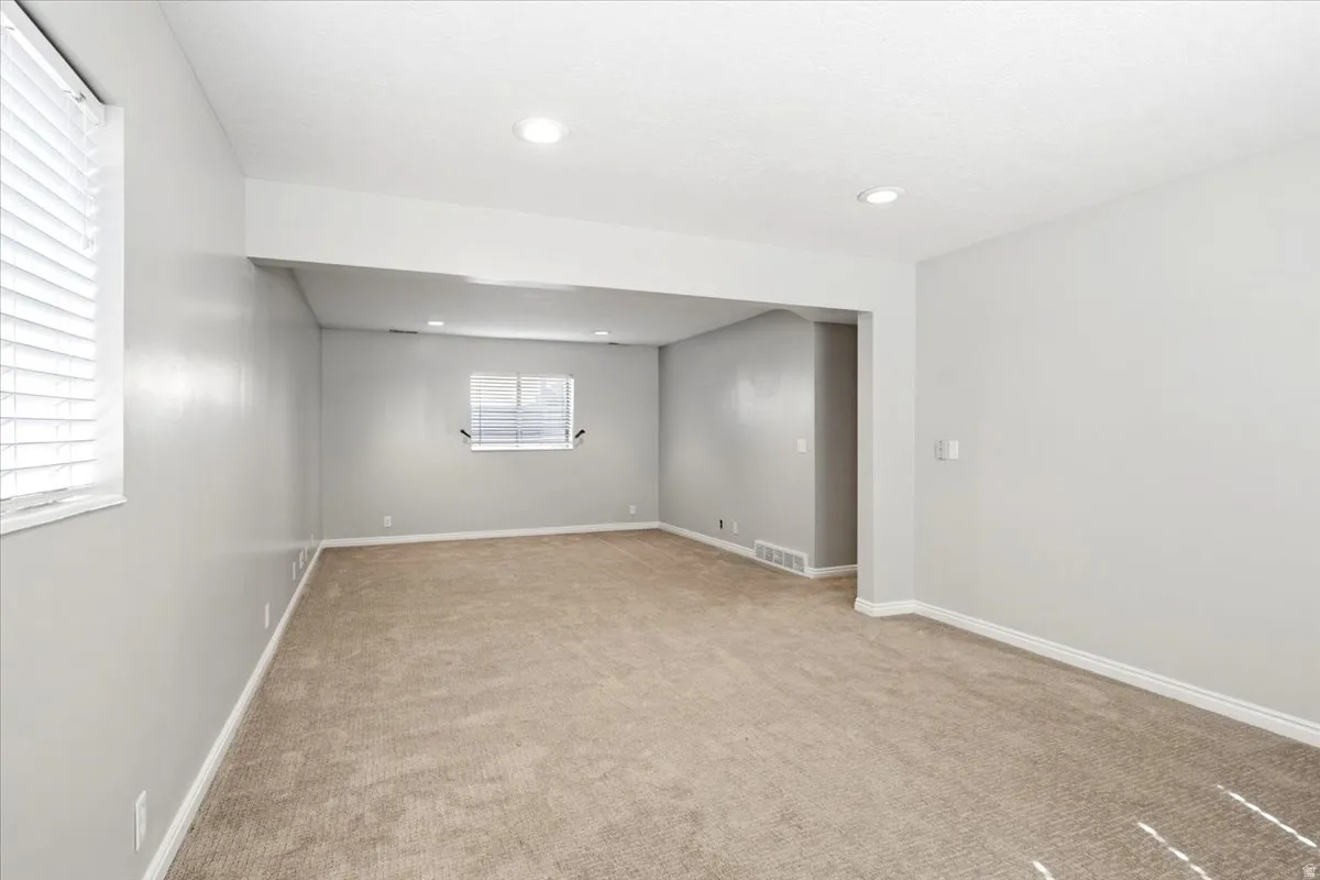 Recessed lighting, neutral tone walls, carpeted flooring, and window blinds