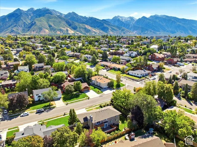 Residential neighborhood with mature trees, paved streets, and mountainous backdrop