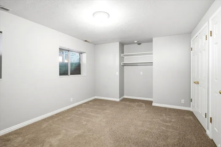 Carpeted room with light neutral walls, a built-in closet with shelving, and two windows