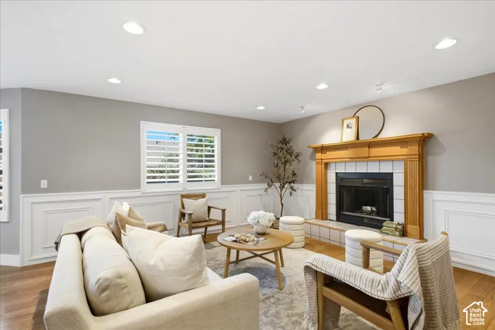 Recessed lighting illuminates the room, featuring wood-finish flooring, wainscoting, and window shutters