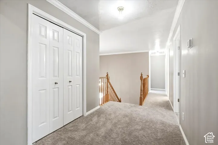 Carpeted hallway with a bi-fold closet, recessed lighting, and a wood spindle railing