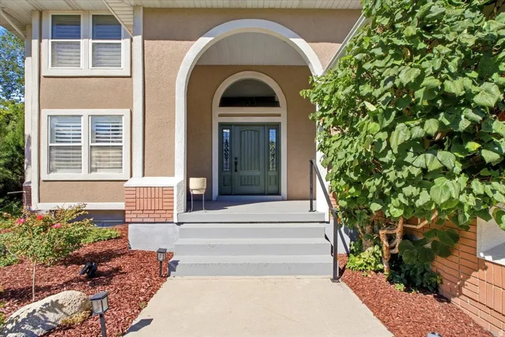 Stucco exterior with an arched entry, a paneled front door with sidelights, and a brick accent foundation