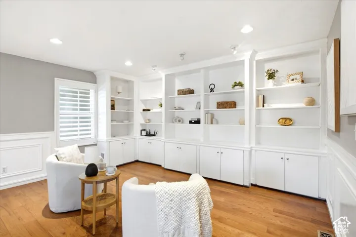 Built-in white shelving and cabinetry, recessed lighting, wood-finish flooring, plantation shutters, and wainscoting with decorative molding