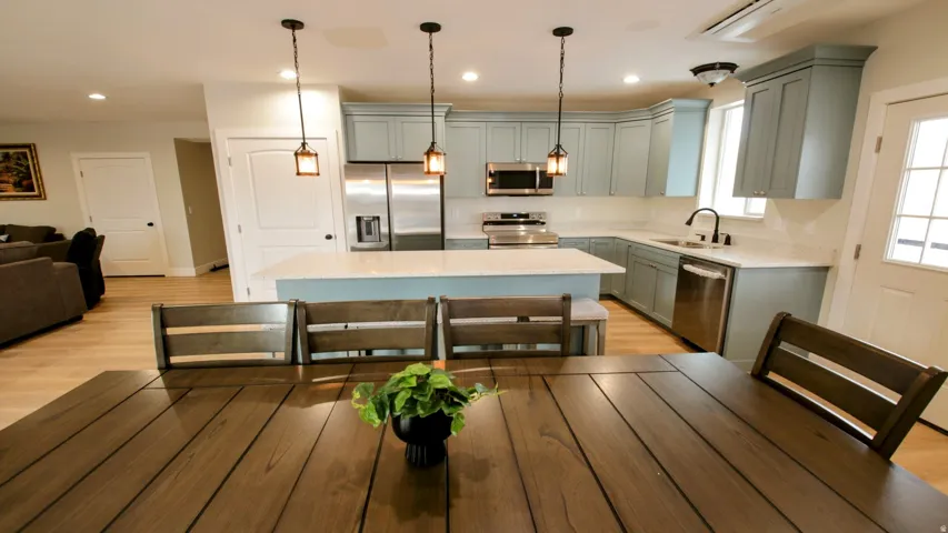 Kitchen featuring light blue cabinetry, stainless steel appliances, an island with countertop seating, white countertops, and wood-finish flooring