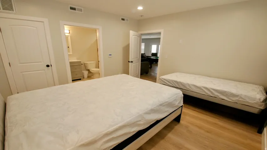 Wood-finish flooring, recessed lighting, and a white interior door with a black knob