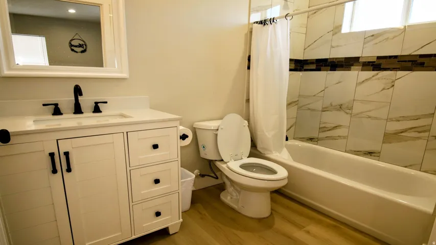 White wood-finish vanity with an integrated sink and matte black fixtures