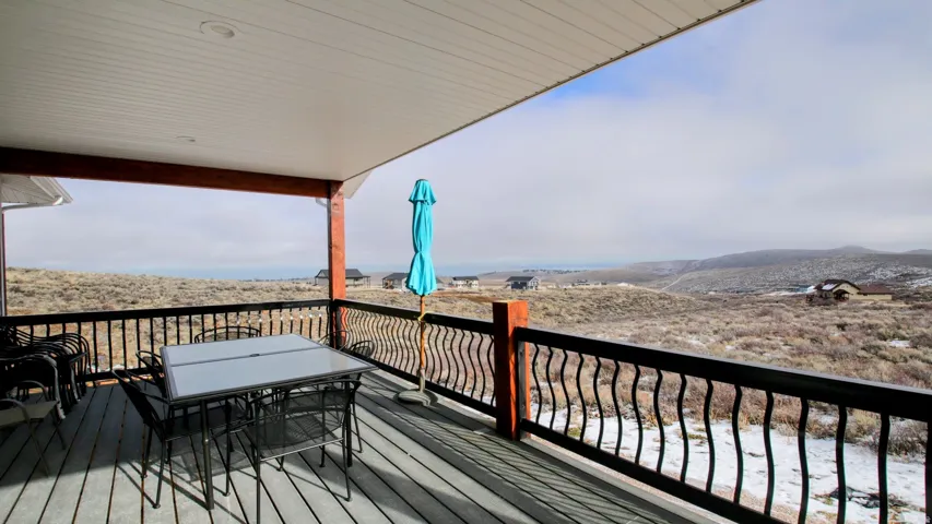 Covered deck with a white soffit ceiling, recessed lighting, and a black wrought iron railing