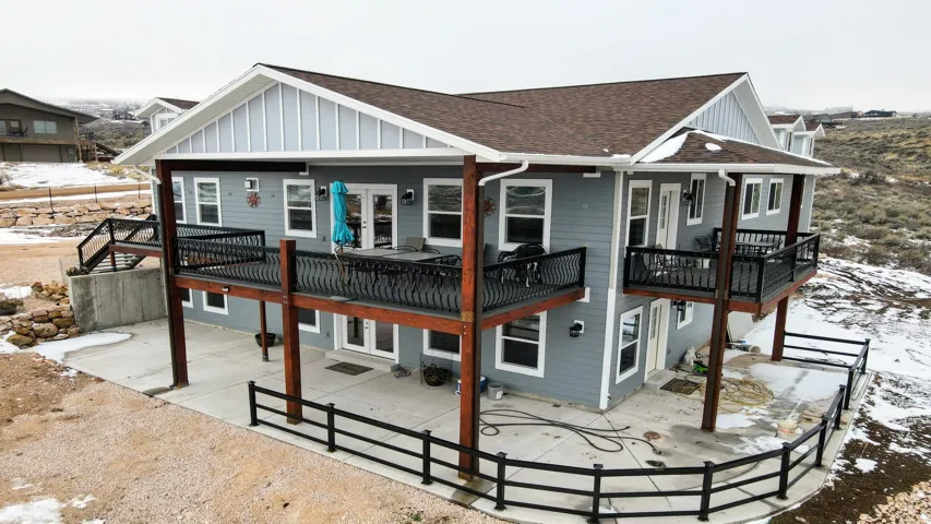 Multi-level residence featuring a brown shingle roof, light gray siding, and multiple outdoor decks with black metal railings