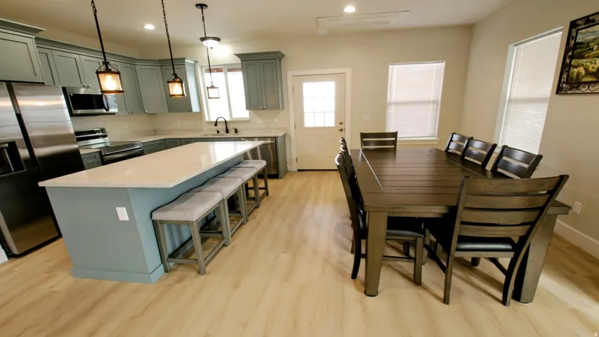 Kitchen and dining area featuring light wood-finish flooring, recessed lighting, and a kitchen island with stone countertops