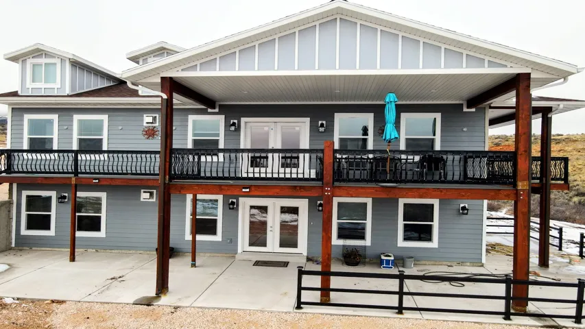 Two-story exterior with a covered upper deck, lower patio, multiple windows, and dormer windows