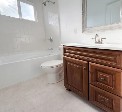 White tile shower surround with chrome fixtures, built-in bathtub, and a window for natural light