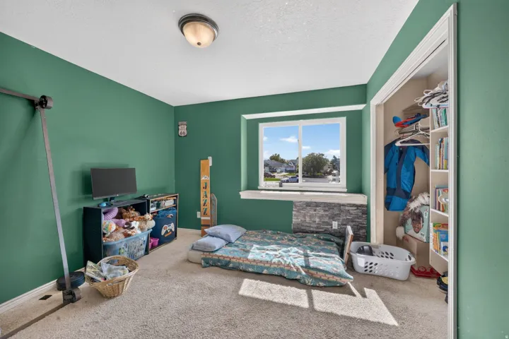 Carpeted room featuring a window with stone-look detailing and a built-in closet with shelving
