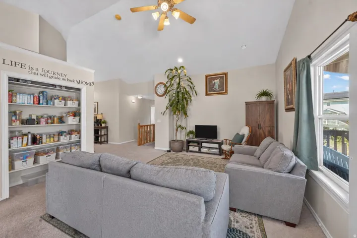Vaulted ceiling with an attached ceiling fan and recessed lighting, large window with a white frame, built-in shelving, and carpeted flooring