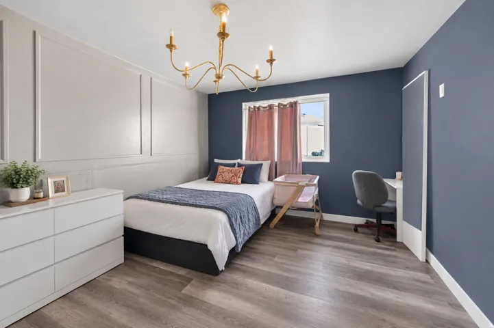 Wood-finish flooring, accent wall with decorative molding, ceiling-mounted light fixture, built-in window, and a built-in desk