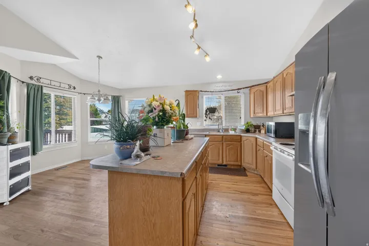 Kitchen featuring wood-finish flooring, a central island, light wood cabinetry, and a stainless steel refrigerator