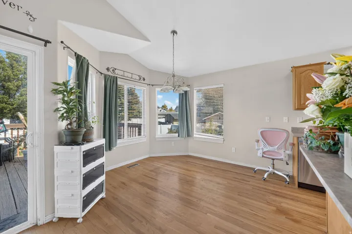 Hardwood-finish flooring, bay window with multiple panes, vaulted ceiling, and sliding glass door