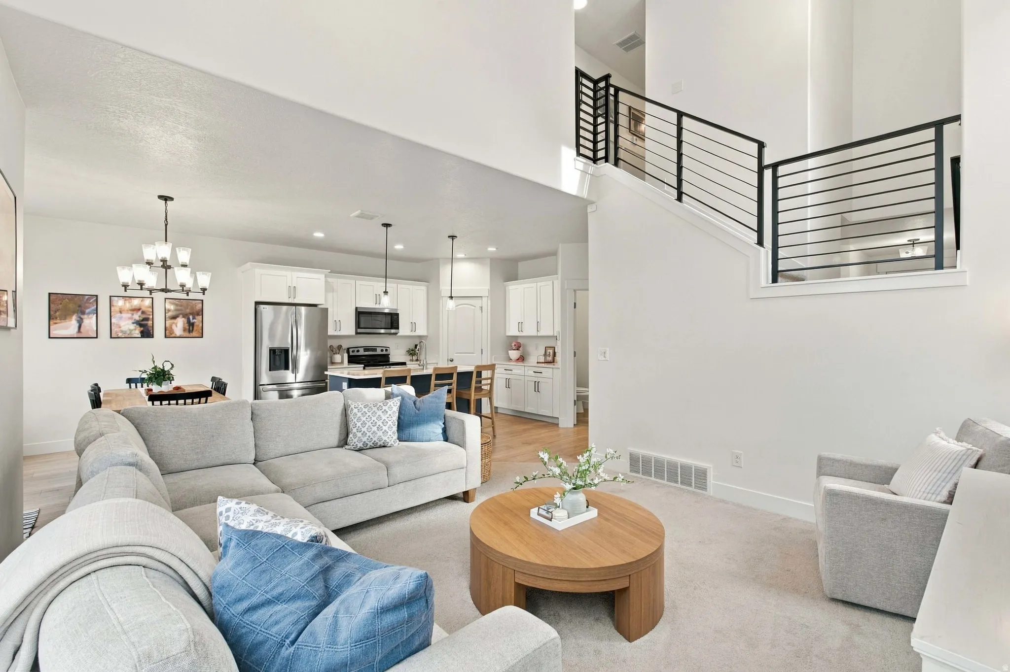 Open concept living area with high ceilings, contemporary metal staircase railing, recessed lighting, and a kitchen featuring stainless steel appliances