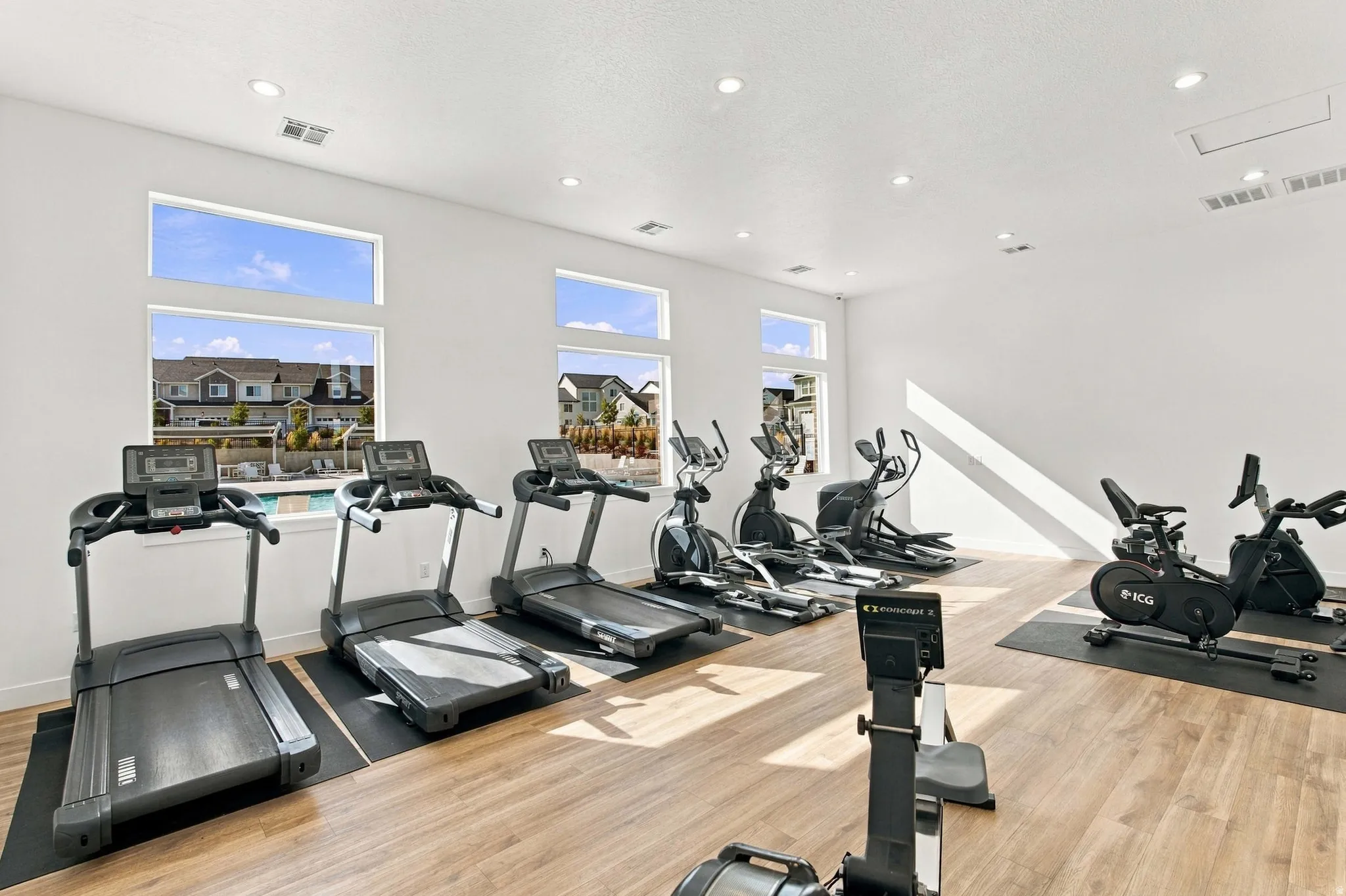 Fitness center with wood-finish flooring, recessed lighting, and multiple windows