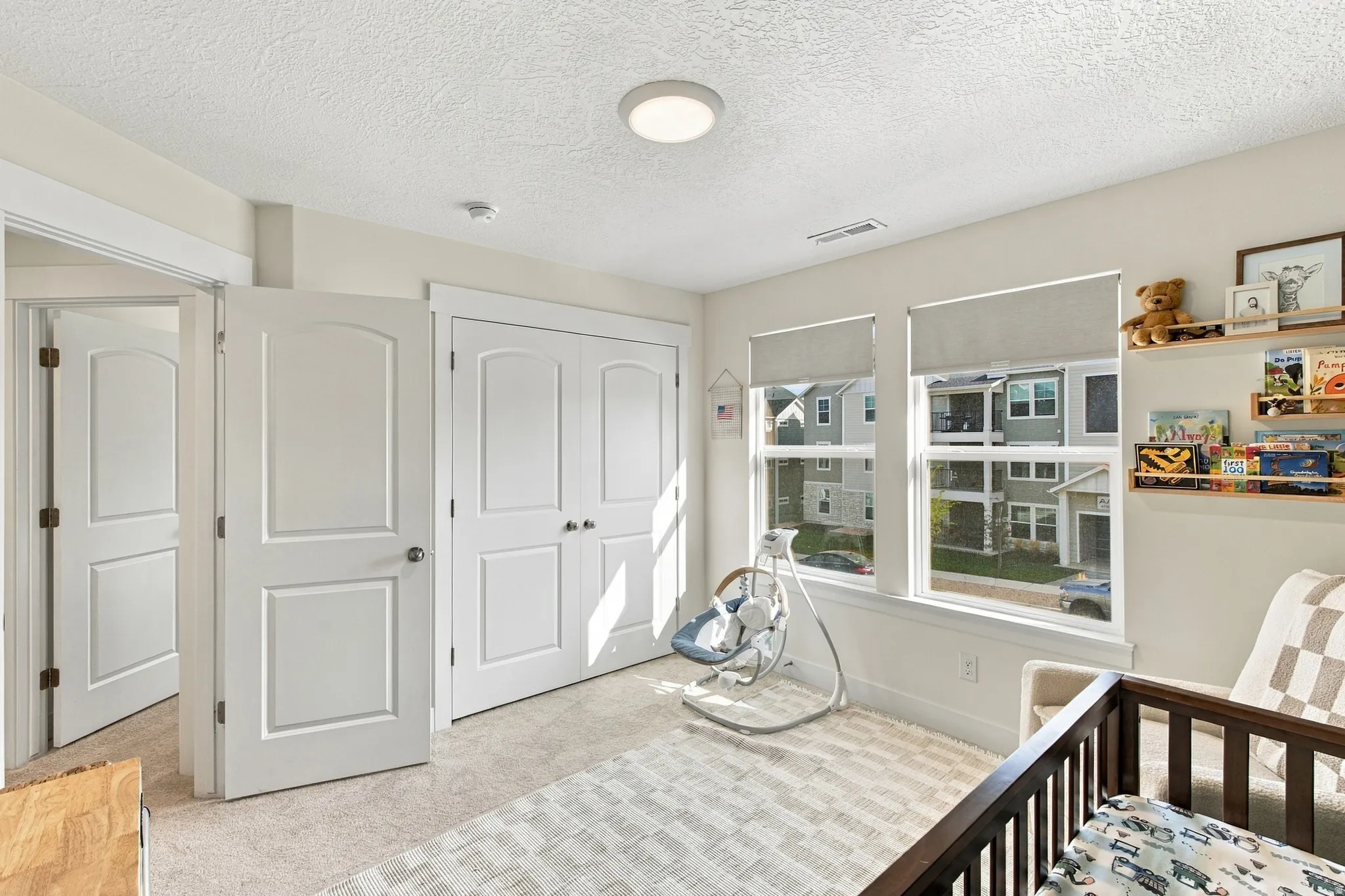 Recessed lighting, two paneled doors, carpet flooring, and two windows with roller shades