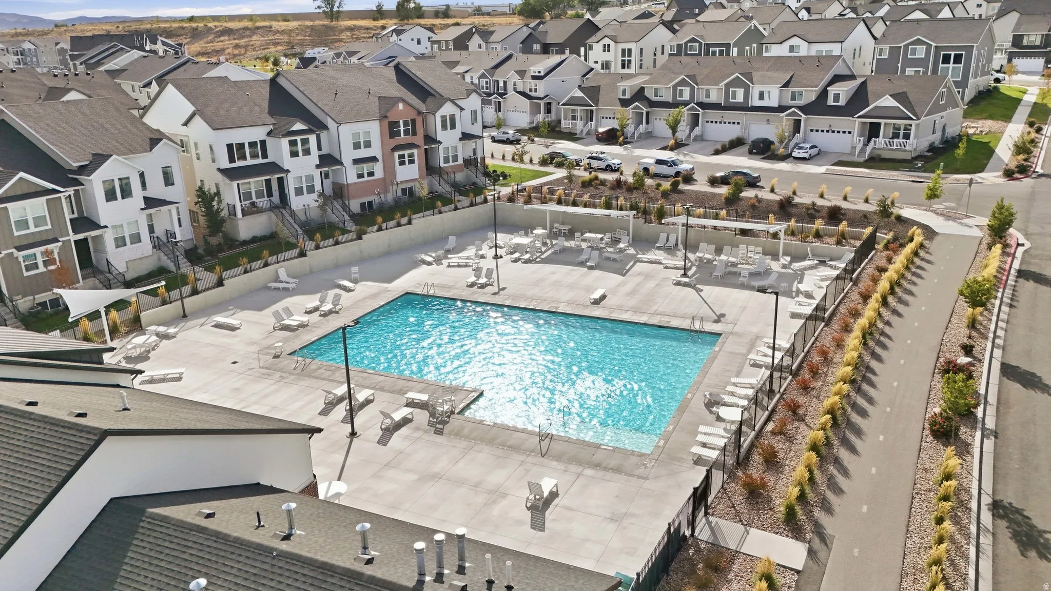 Community swimming pool with surrounding lounge deck, perimeter fencing, and a pedestrian pathway